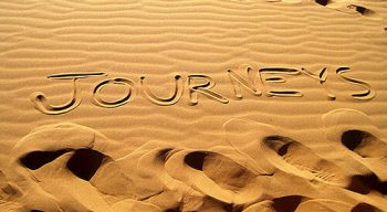 "Journeys" written in the sand