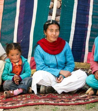 Women and children sit on rug in Ladakh