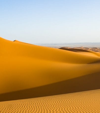 Group of travelers stand on top of sand dune