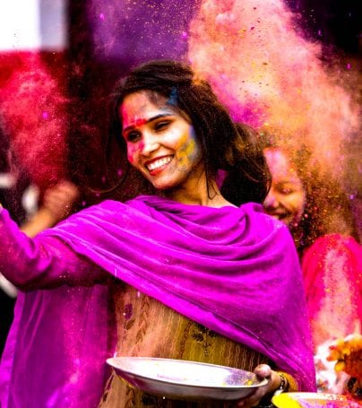 Woman dances at Holi Festival with colorful dust