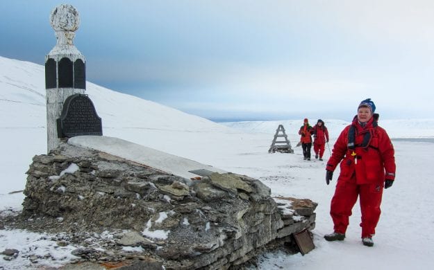Woman stands next to monument in the Arctic