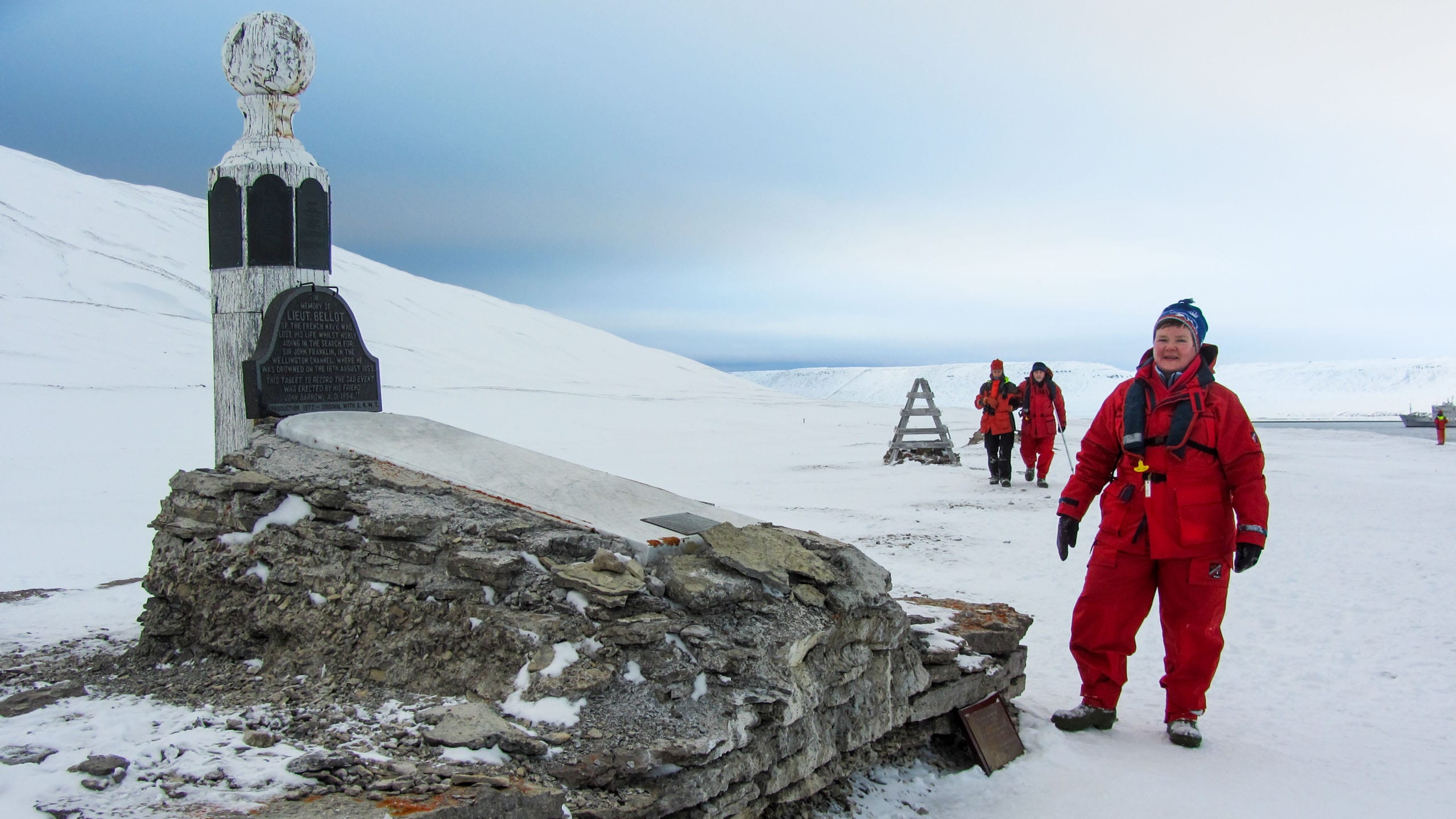 Woman stands next to monument in the Arctic