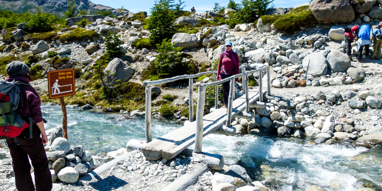 Hiking group crosses wooden bridge in Argentina