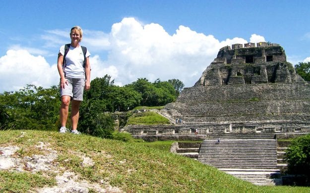 Woman stands on hill near Mayan temple in Belize