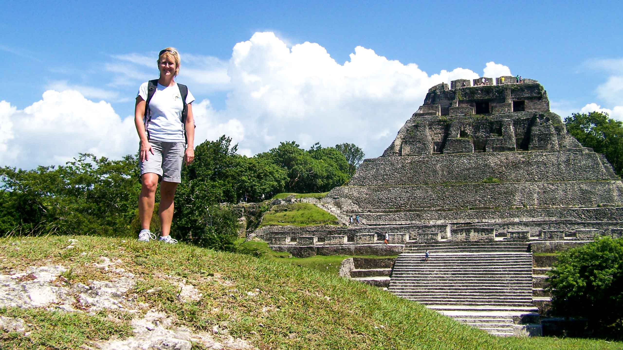 Woman stands on hill near Mayan temple in Belize