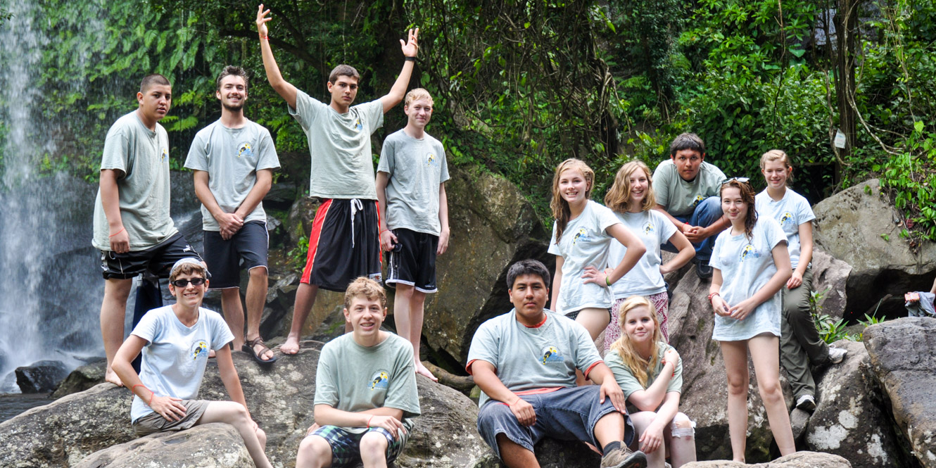 Group of teens sit on rocks in Cambodia