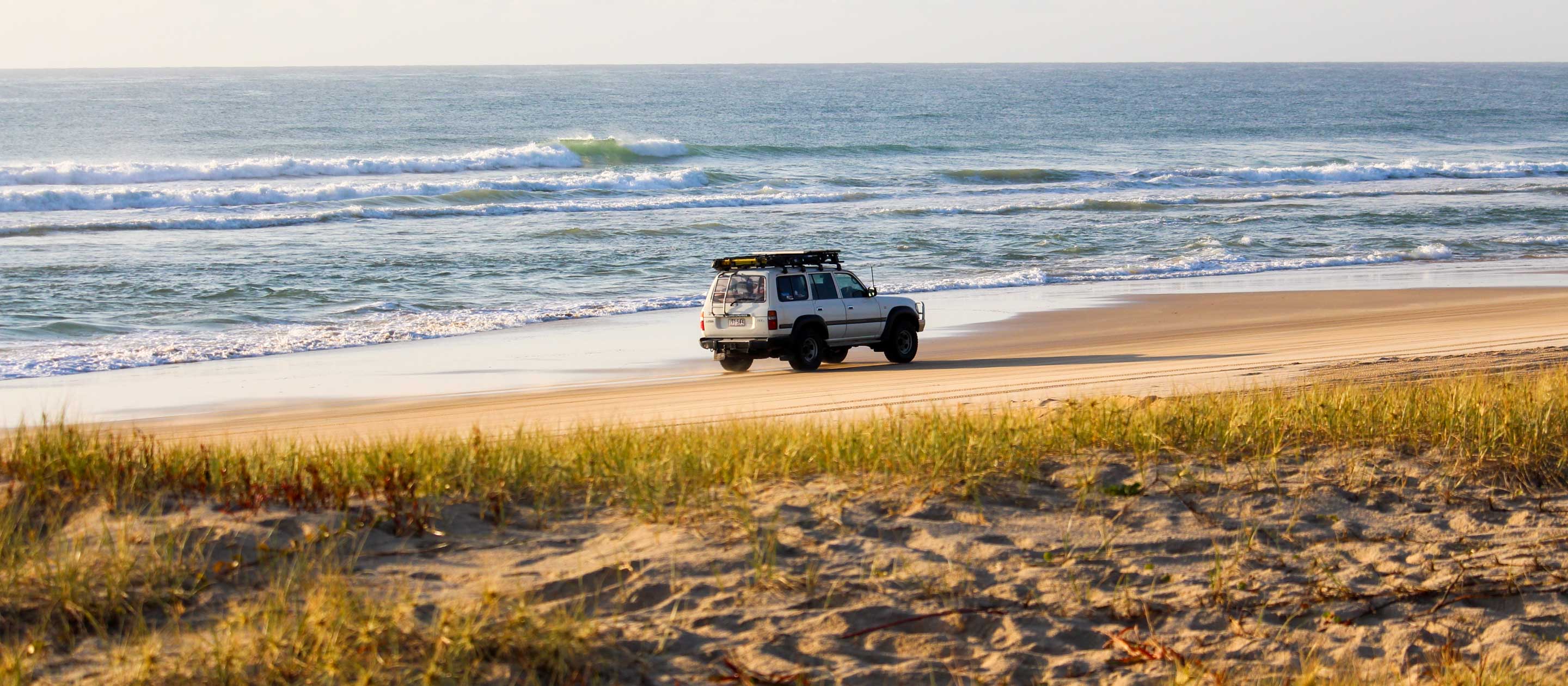 Car driving down beach of Fraser Island, Australia