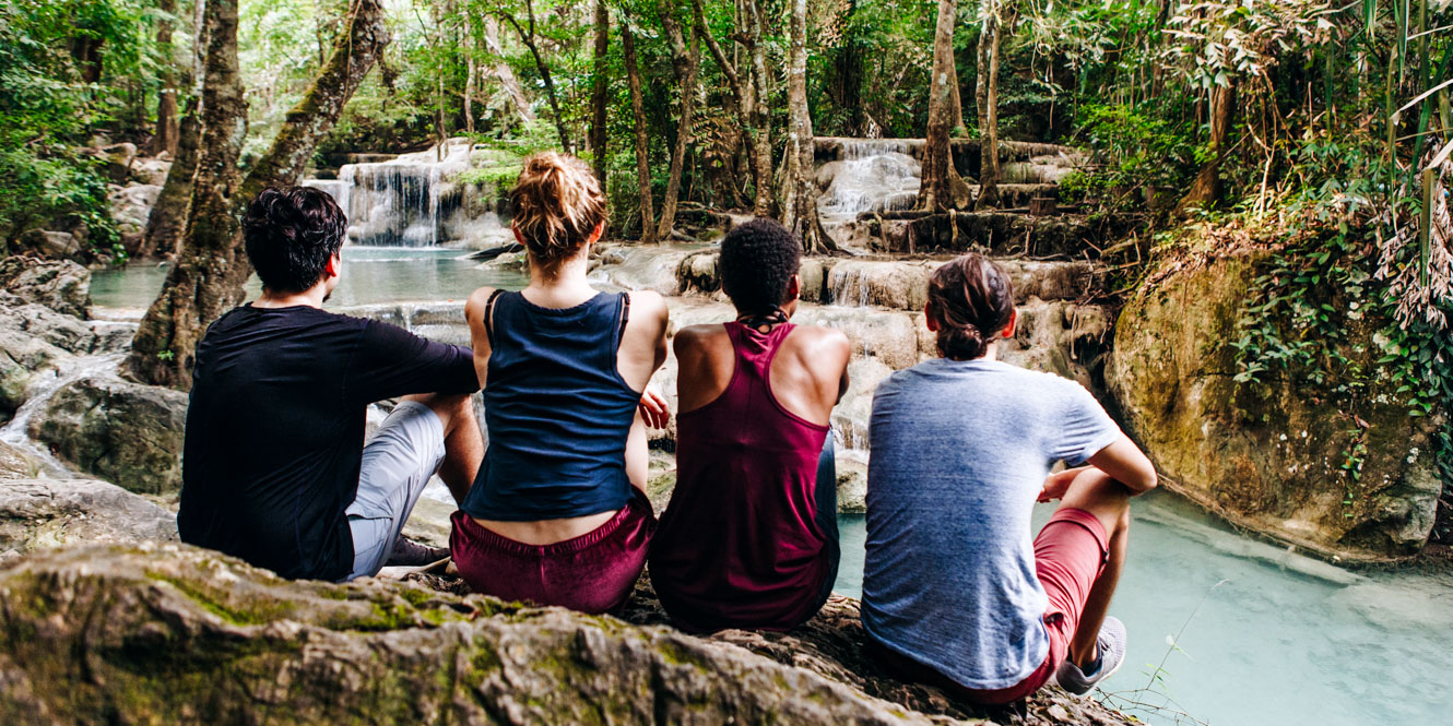 Group of college students sit on rock by river