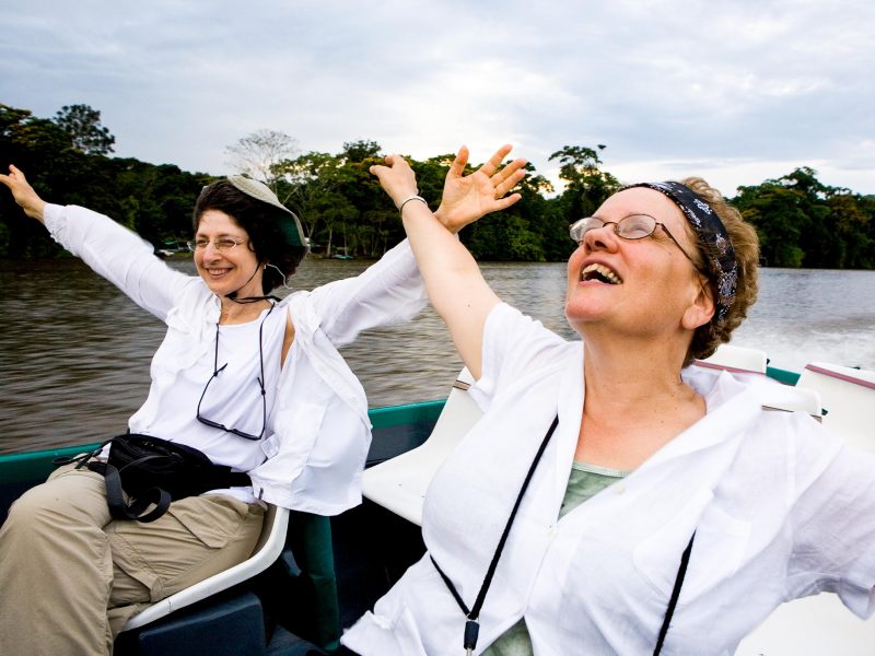 Women spread arms in joy on boat trip