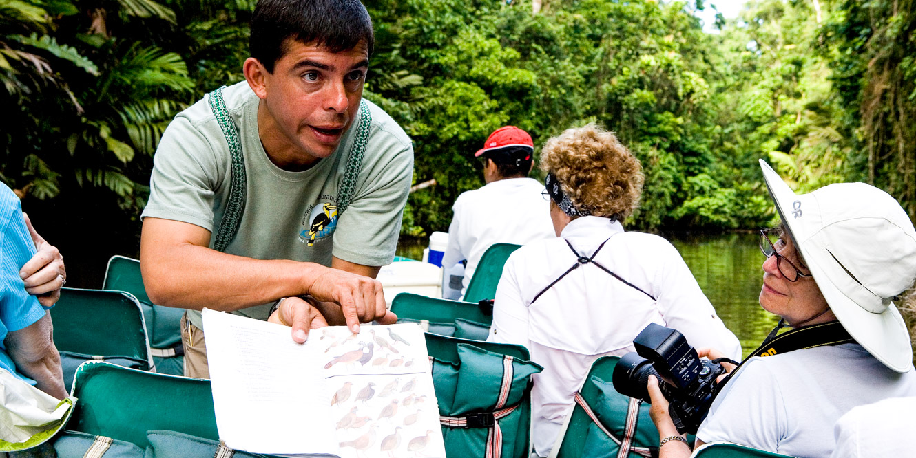 Guide shows bird book to boat tour group