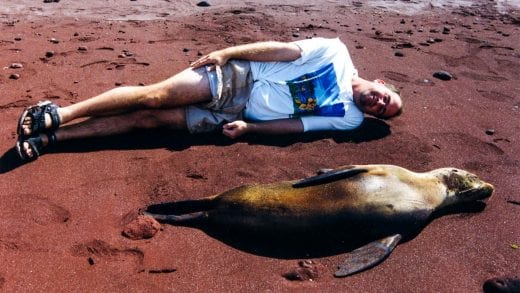 Traveler lies next to seal in Galapagos