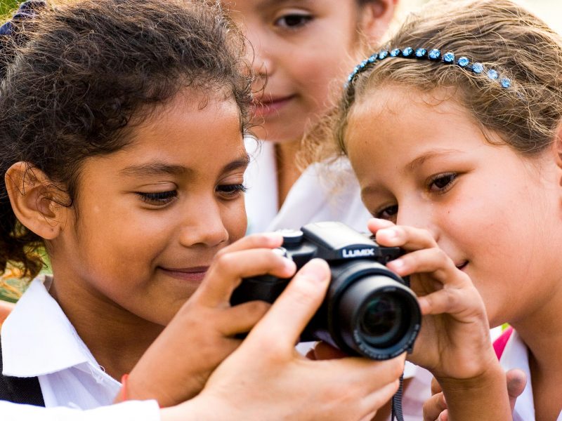 Young girls look at back of digital camera