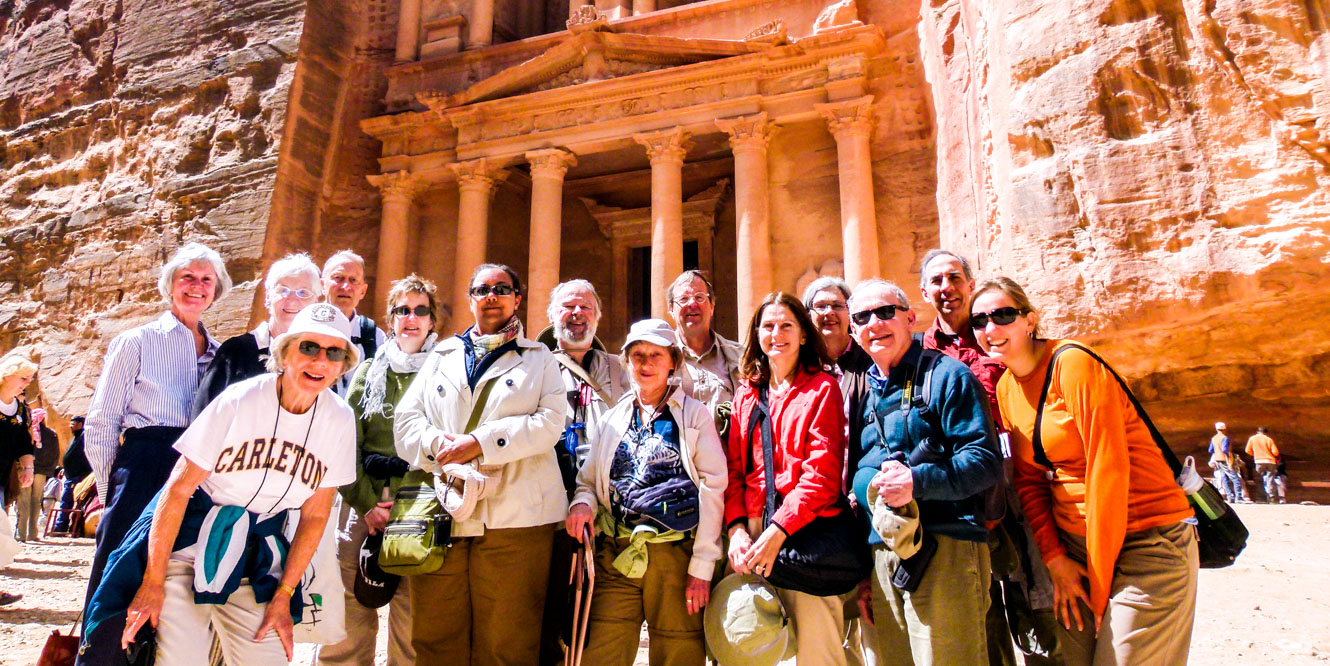 Group of travelers stands in front of Jordan cliff temple