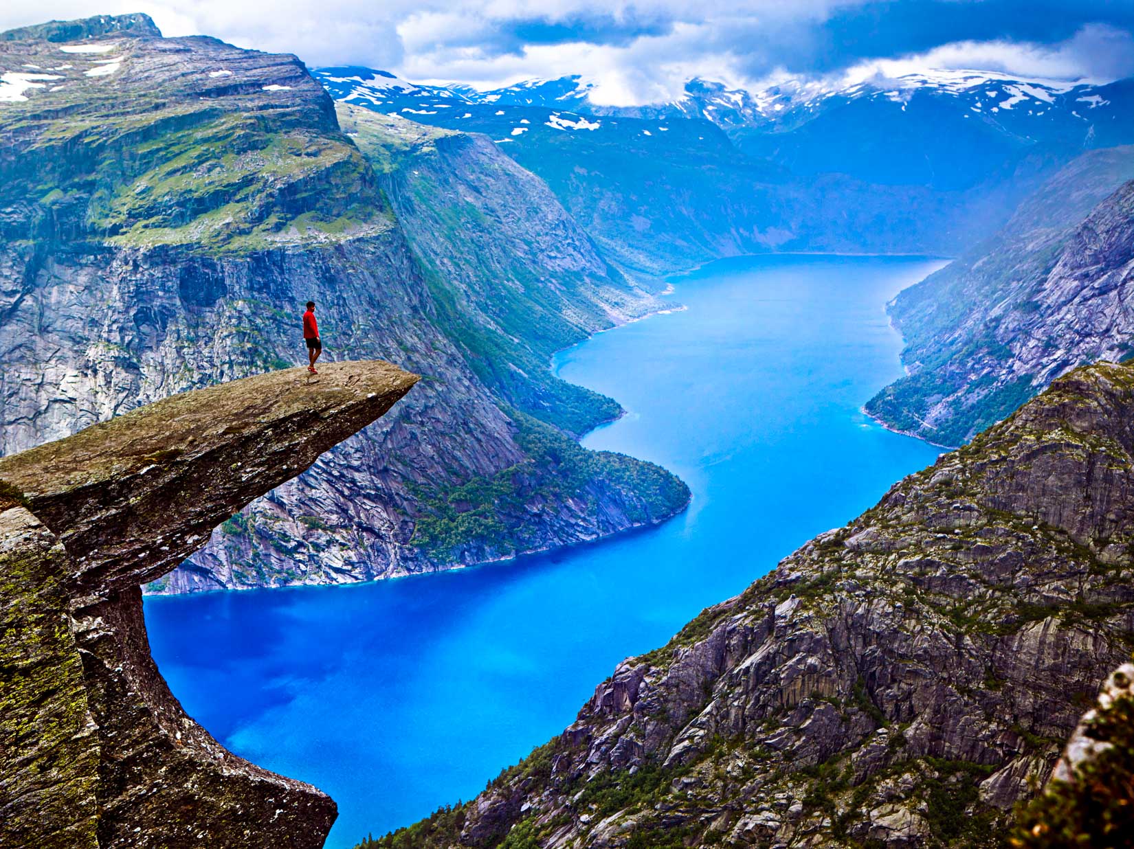 Hiker stands on rocky overlook in Norway