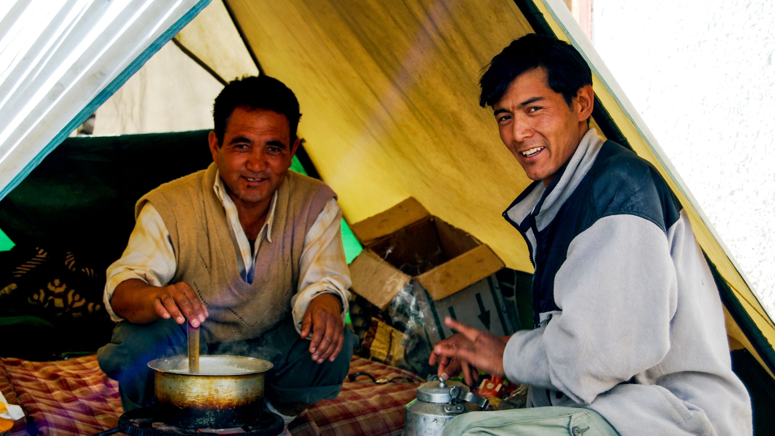 Two men sit to eat dinner in Ladakh tent