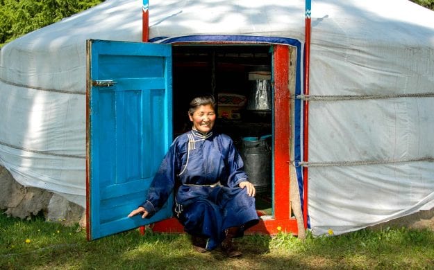 Mongolian person sits in front of ger