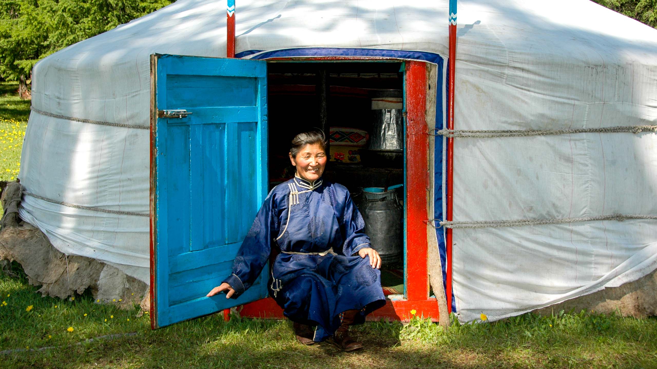 Mongolian person sits in front of ger