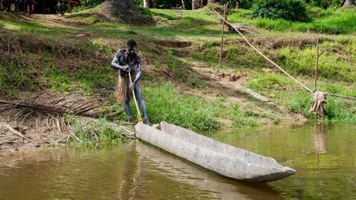 Papua New Guinea man pushes boat into river