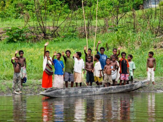 Group of children waves from the bank of a river