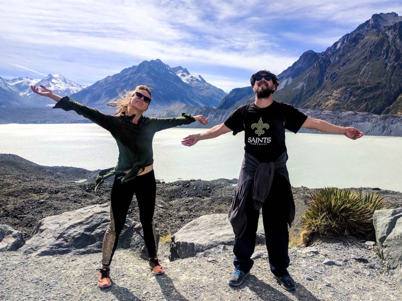 Travelers hold arms out joyfully near lake