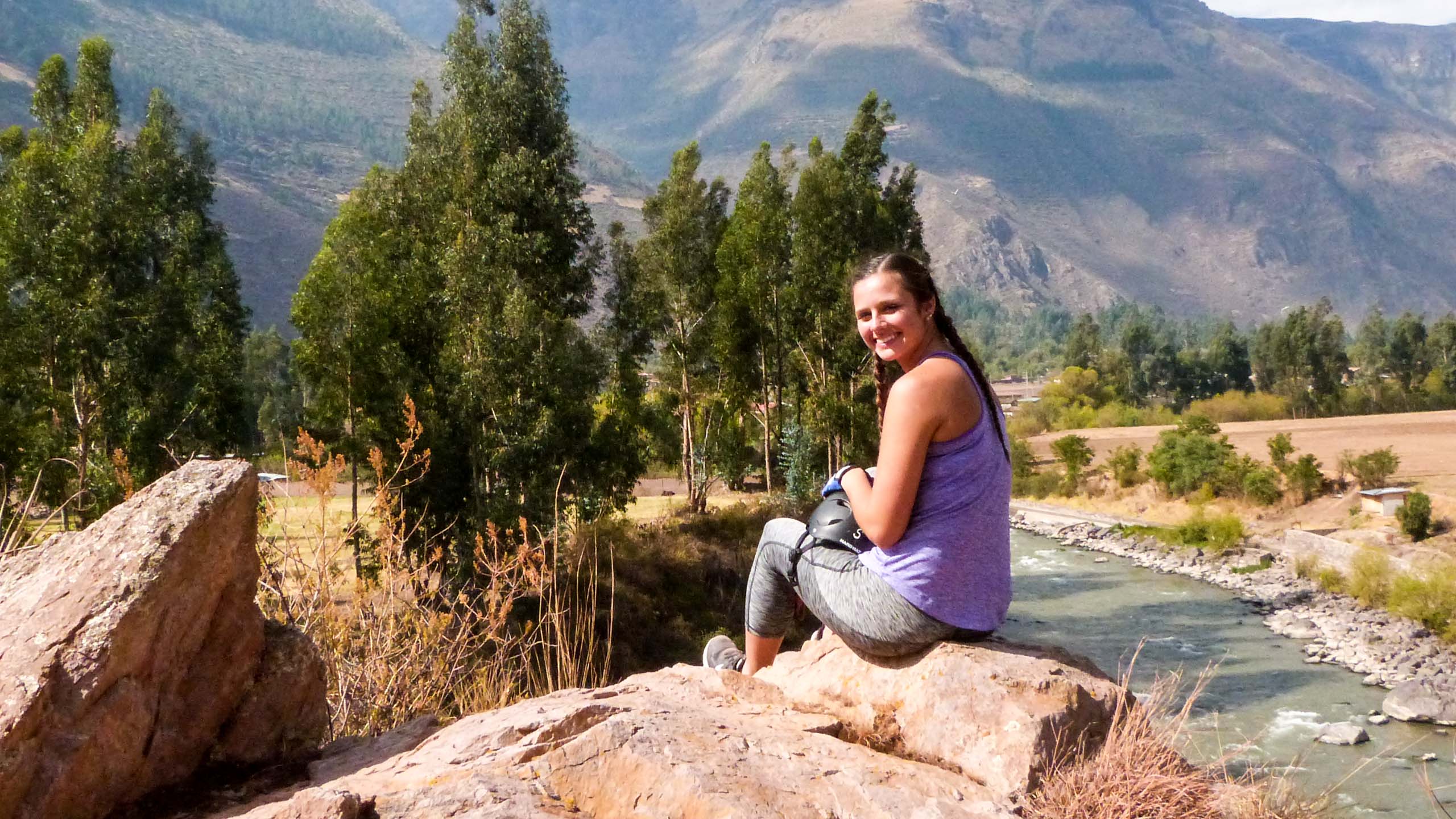 Woman sits on rock while hiking in Peru