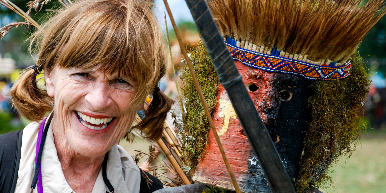 Smiling traveler with masked Papua New Guinea native