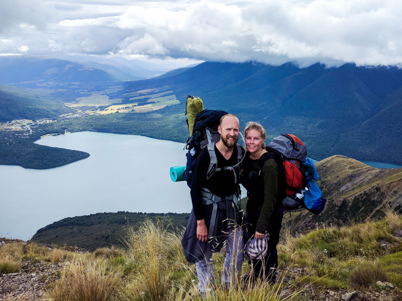 Two hikers stand in front of New Zealand lake