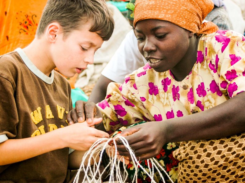 Kenyan woman show boy how to weave