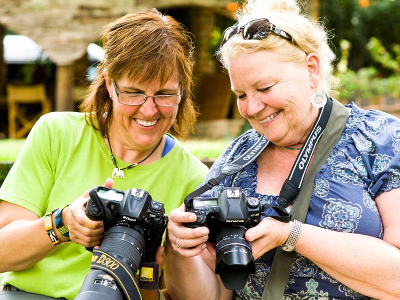 Two smiling women look at their cameras