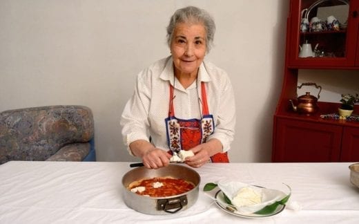 Older woman slicing cheese for pizza