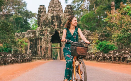 Young woman riding bicycle in Angkor Wat