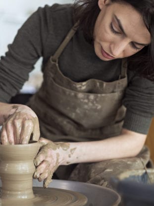 woman spinning pottery on wheel