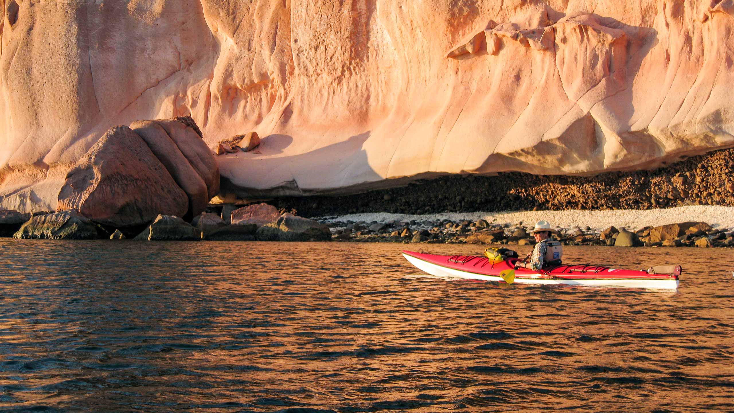 Man kayaking alone with rocky cliff beyond in Baja, Mexico