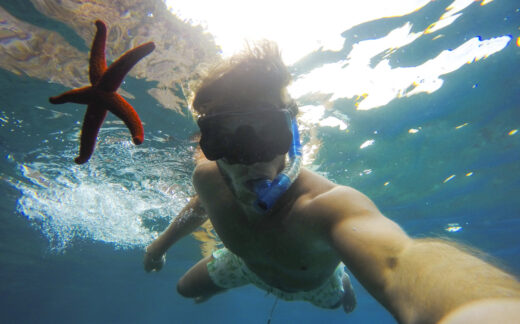 selfie of teenage boy snorkeling underwater with starfish