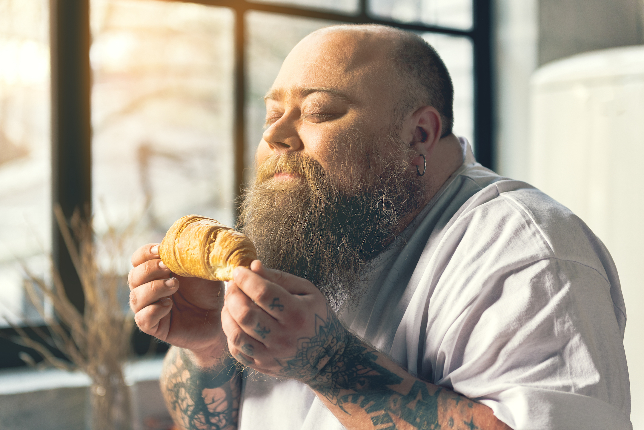 Man with tattoos smelling croissant
