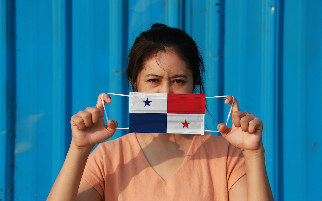 woman holding face mask shaped like Panama flag in front of face