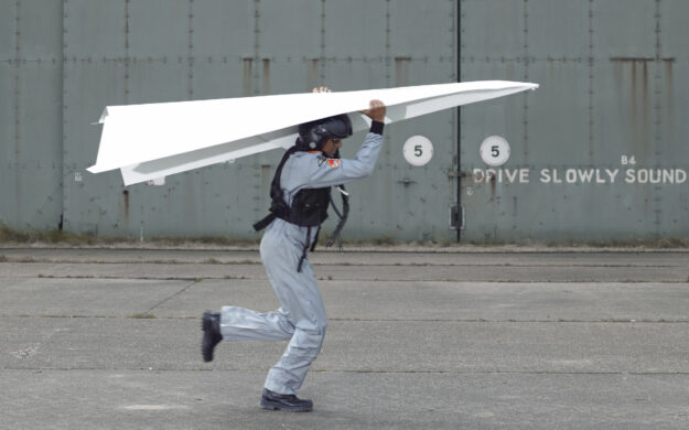 Man holding giant paper airplane over his head