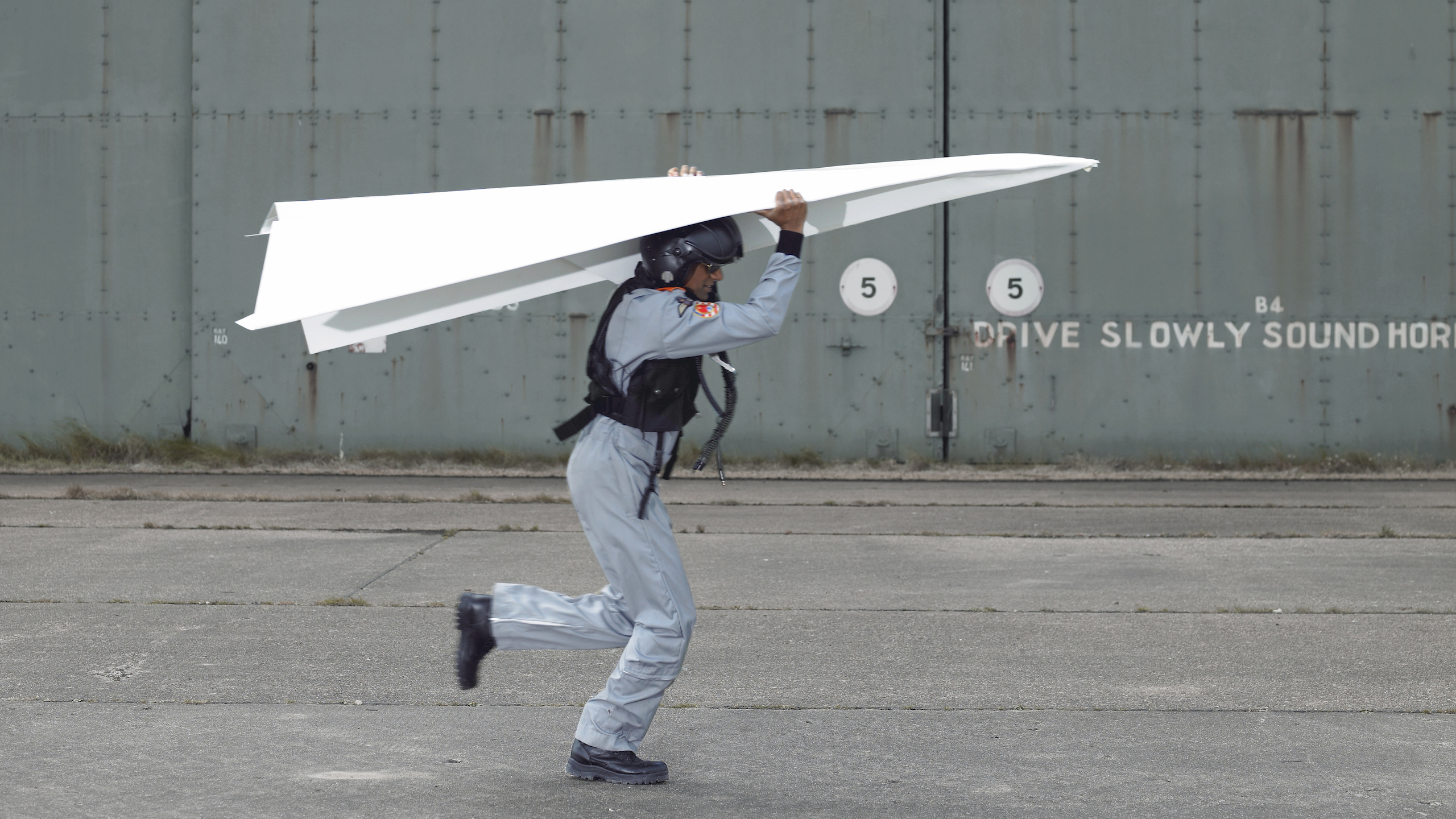 Man holding giant paper airplane over his head