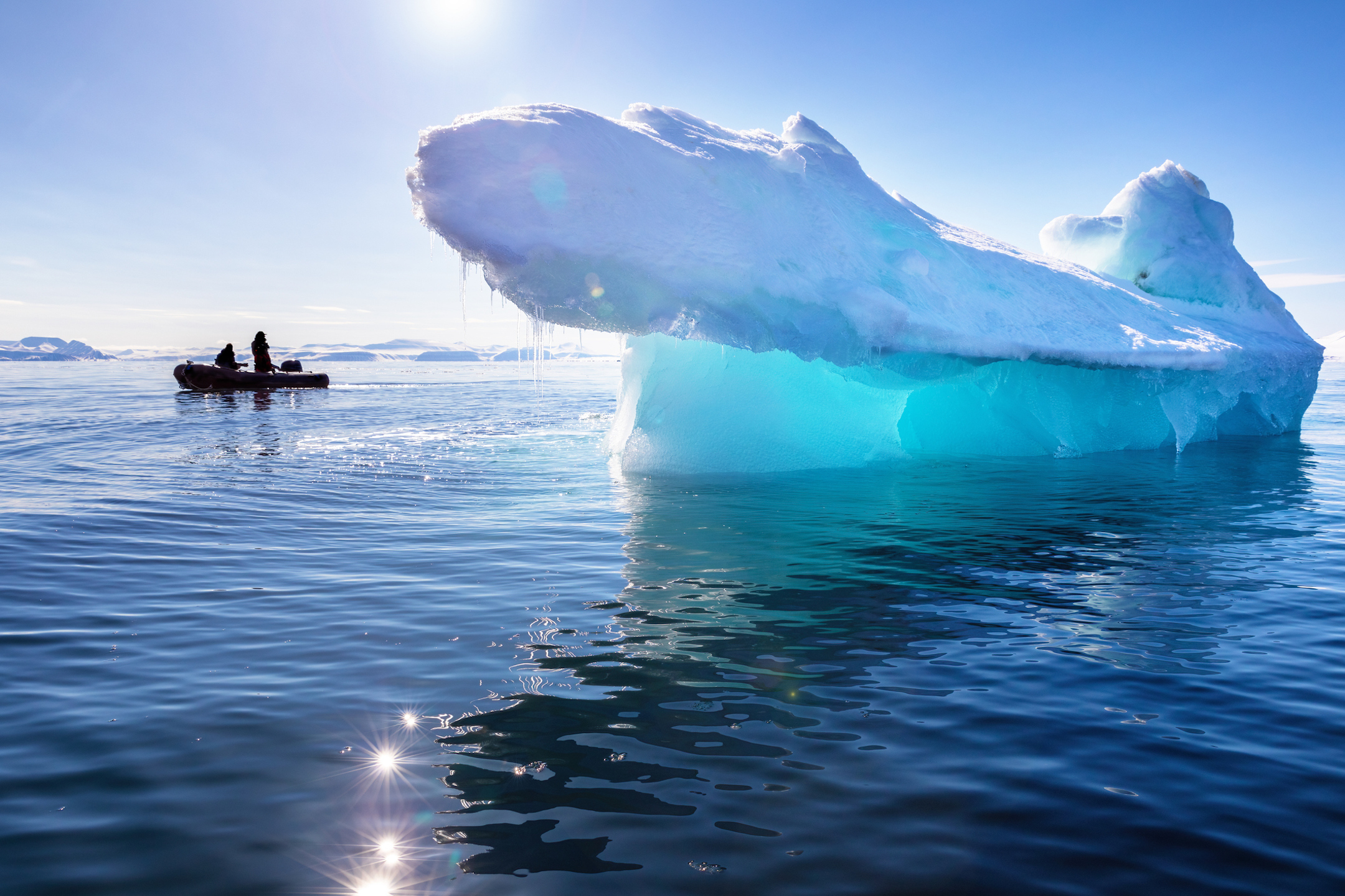 small boat next to bright blue iceberg