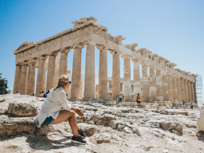 Woman relaxing while looking at Parthenon temple against clear sky