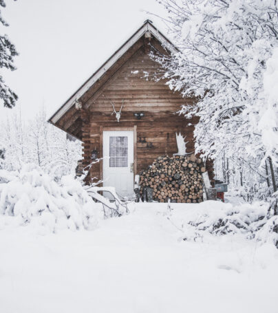 A cozy log cabin in the forest at winter time with lots of snow around